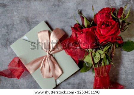 
Envelope with a love confession and a bouquet of red roses for the beloved woman in honor of Valentine's Day on a gray background