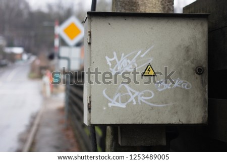 Grey Hinged Power Supply Box with graffiti.