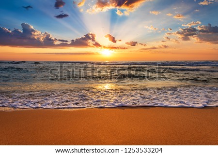 Colorful ocean beach sunrise with deep blue sky and sun rays. Royalty-Free Stock Photo #1253533204