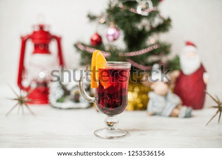 Christmas decor, tree, gold pumpkin, deer, gift, Santa, star, gingerbread house, red lantern on the wooden table. White wood background Hot mulled wine drink with orange in a glass cup Christmas eve