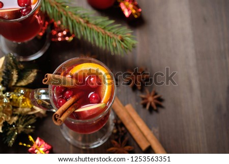 Mulled wine on a wooden background with candles, pine branches and Christmas lights