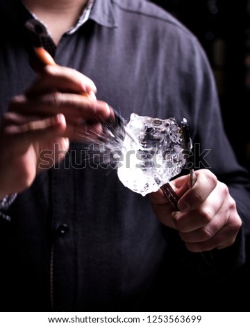 Bartender making refreshing coctail on a bar background. Dark moody style. Ice in tha glass