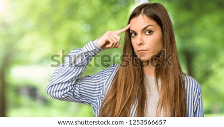 Young girl with striped shirt making the gesture of madness putting finger on the head at outdoors