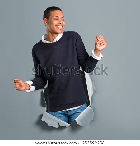 Young african american man enjoy dancing while listening to music at a party through a paper hole