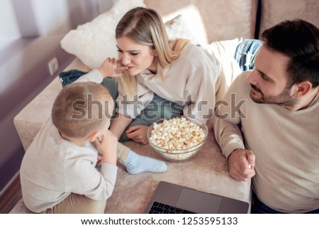 Portrait of a cheerful young family having fun together. They using laptop in living room.