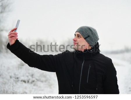 Guy takes pictures photo on the smart phone winter nature