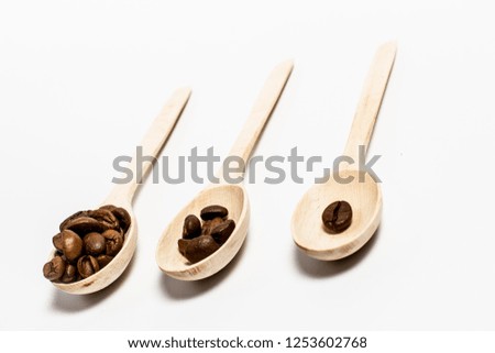 Three wooden spoons with fragrant coffee grains on a white background