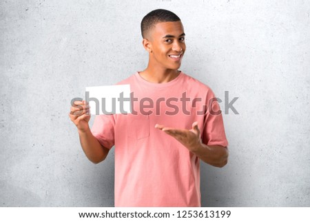 Young african american man holding an empty white placard for insert a concept