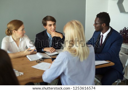 team of young businessmen men and women discuss business at work in the office at the table