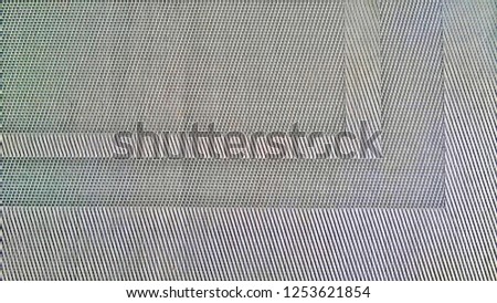The texture and background of a piece or part of a silver kitchen or dining mat bedding for dishes from a special or artificial fabric resembling metal or iron.