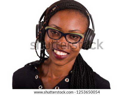young african woman in glasses isolated on white background smiling and listening to music using a headphones.