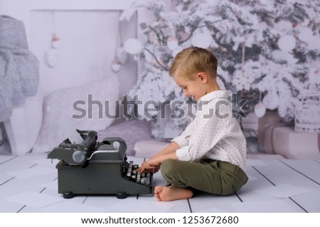 The boy opens Christmas presents from Santa Claus. Studio shot. In the background a white Christmas tree.