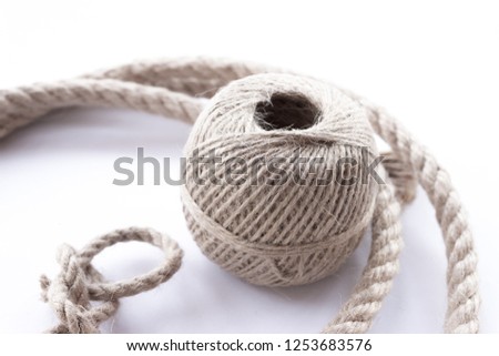 Thin twine tangled in a ball and rope witk dragon loop. There are several threads of rope around the ball.