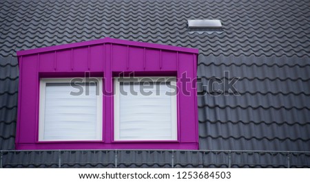 Selectively colorized photo of modern classic architecture fragment featuring tiled roof and attic. Mansard or mezzanine with purple / violet / magenta window.
