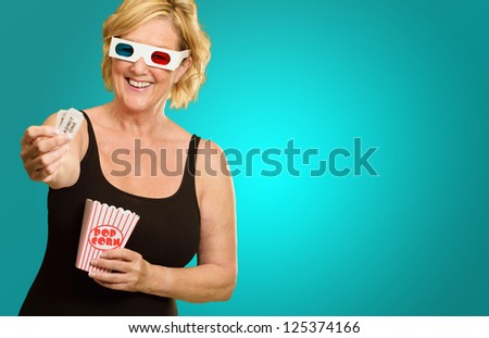 Happy Elderly Woman Wearing 3d Glasses Holding Popcorn And Ticket On Coloured Background