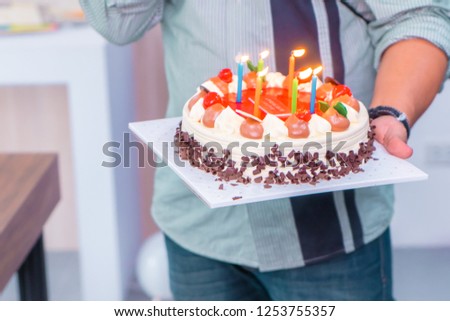 Daddy is lighting birthday candles on birthday cake for children brithday party