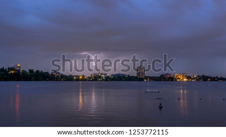 A Wide Angle Long Exposure Shot of a Lightning Bolt over Lake Bde Maka Ska in Minneapolis as a Swimmer Watches during a Summer Twilight