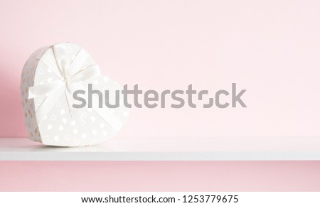 Luxury white gift boxes with white ribbon form of heart on shelf on pastel pink background wall. Concept holiday. Happy Woman's Day, Mother's Day, Valentine's Day, Wedding