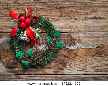 Merry christmas text decorations with Bell, green pine and red ribbon on the old wood board by Flat lay, top view and copy space. In concept, happy with the holidays in the new year.