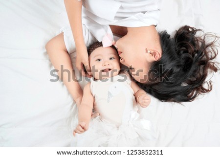 Mother kisses baby lying on the bed closeup