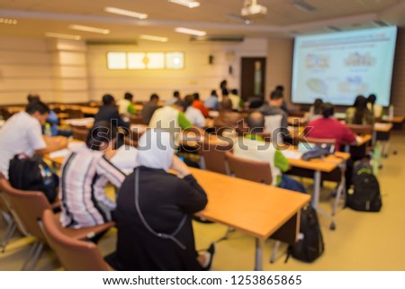 Abstract blur of people or participant are training in the lecture room with lecturer presented the presentation by a projector and a screen of the projector