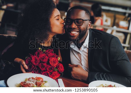 African American Couple Dating in Restaurant. Romantic Couple in Love Dating. Cutel Man and Girl in a Restaurant Making Order. Romantic Concept. Girl Kissing Man. Bouquet of Flowers. Red Roses. Royalty-Free Stock Photo #1253890105