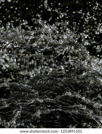 Water splash in dark with a drops of water flying, defocused bokeh.