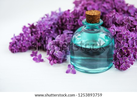 Essential oil with lilac flowers on a white wooden background