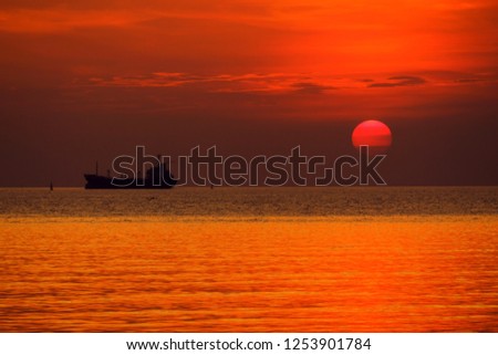 Sunset and black silhouette ship on sea.