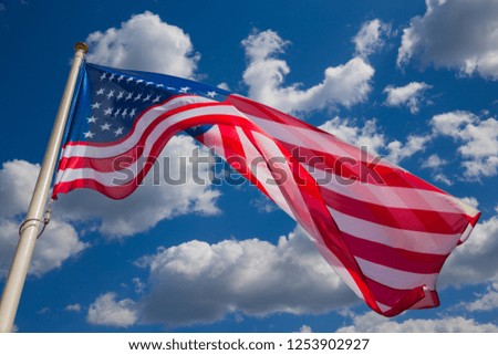 American flag against a blue sky with clouds
