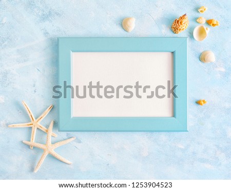 Flat lay top view Summer vacation mockup: photo frame, seashells and white starfish on blue background. Travel, beach concept. Space for text or lettering