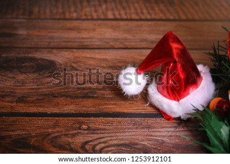Holidays, christmas, costume and tradition concept - close up of santa hat on wooden table over lights background.