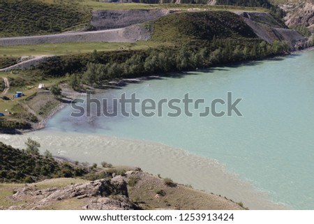 Excellent mountain landscape with the place of merging mountain rivers "Catun" of turquoise color and river "Chuya" of gray. Filage view of the mountains and the river. Russia, Mountain Altai.