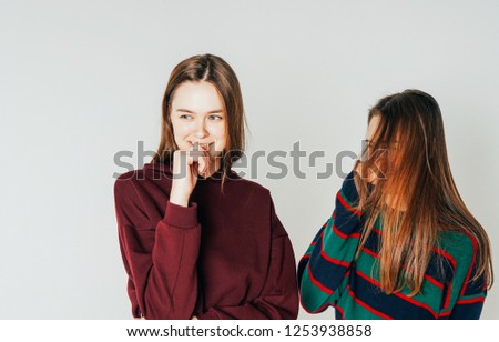 Two sisters twins beautiful girls hipsters in casual clothing laughing on grey background isolated