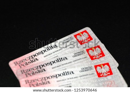 Selective focus. Polish Identity Cards, with Coat of arms of Poland (white, crowned eagle on a red background). Translation of description: Republic of Poland, Identity Card. Black background