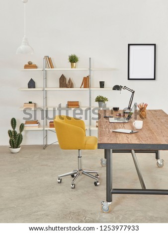 Modern office room, decorative wooden table yellow chair and bookshelf background, white wall with frame.