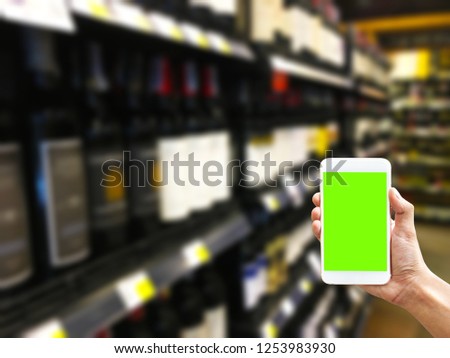 Handing a green screen smartphone to use an application about shopping or finding a place to buy a liquor , wine on shop in blurred background - can use for business apps concept 