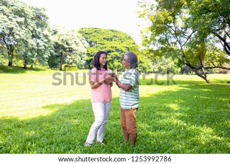 Asian woman relax time in park. A man sent milk for woman.She is drinking milk.She is  smile and be happy in good time ,Life style,Photo concept  out door and healthy.
