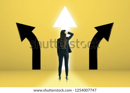 Young businesswoman with arrow choice on yellow background. Different direction and challenge concept 