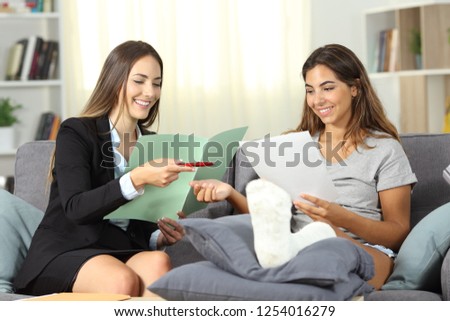 Happy insurance agent and disabled customer singing contract sititng on a couch at home Royalty-Free Stock Photo #1254016279