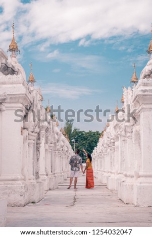 Kuthodaw pagoda in Mandalay, Burma Myanmar, happy young couple men and woman on vacation in Myanmar walking by white temple pagoda the largest book in the world