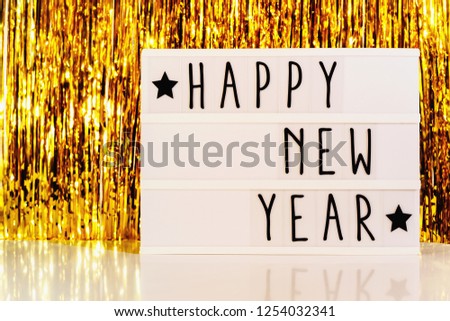 Happy New Year displayed on a vintage lightbox with golden background on the table, concept image