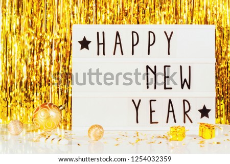 Happy New Year displayed on a vintage lightbox with golden background and decorations, concept image