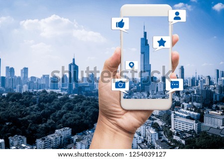 Hand holding mobile smart phone, with notification icons and city background