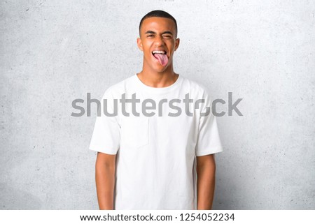 Young african american man showing tongue at the camera having funny look