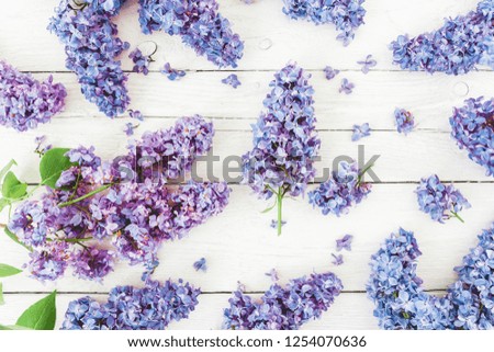 Pattern of lilac flowers branches on wooden background. Flat lay, top view.