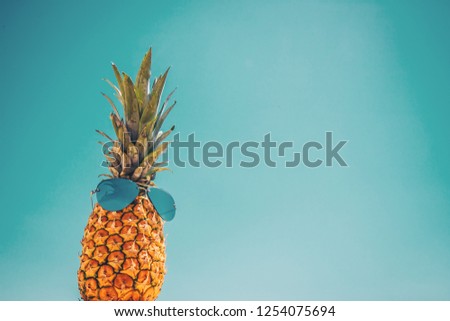 Rear background with a picture of a pineapple in sunglasses against a blue sky - concept