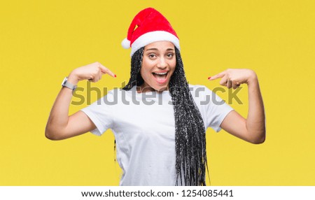 Young braided hair african american girl wearing christmas hat over isolated background looking confident with smile on face, pointing oneself with fingers proud and happy.
