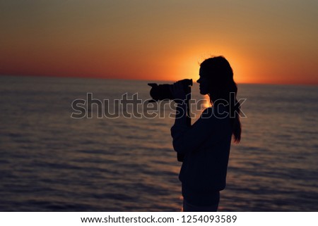 Silhouette woman with camera in hand at the sea                   