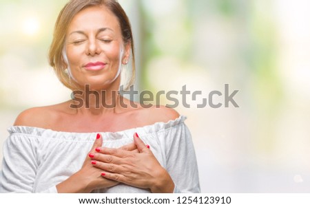 Middle age senior hispanic woman over isolated background smiling with hands on chest with closed eyes and grateful gesture on face. Health concept.
